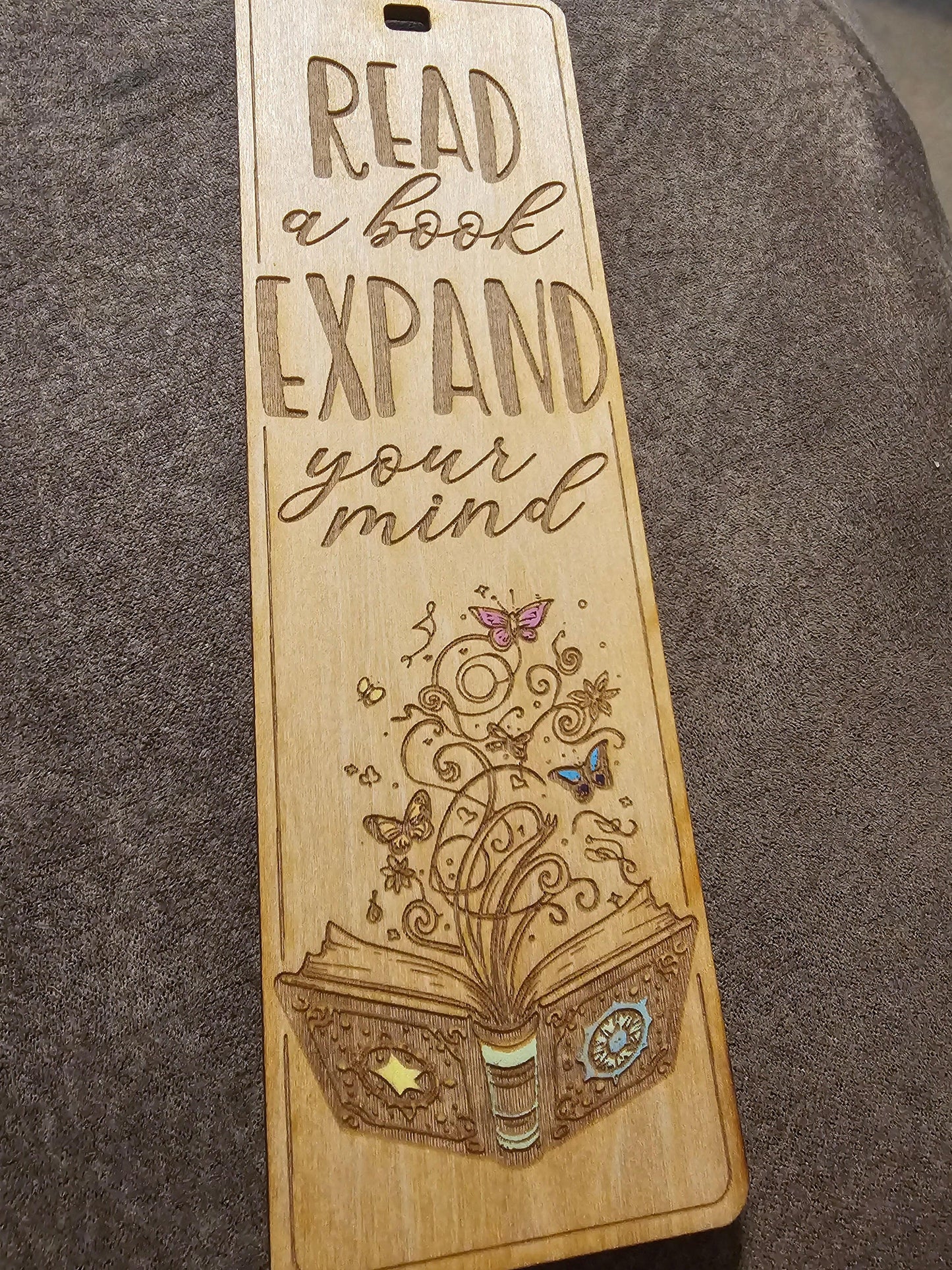 Wooden bookmark with engraved quote 'Read a book, expand your mind' and decorative book art