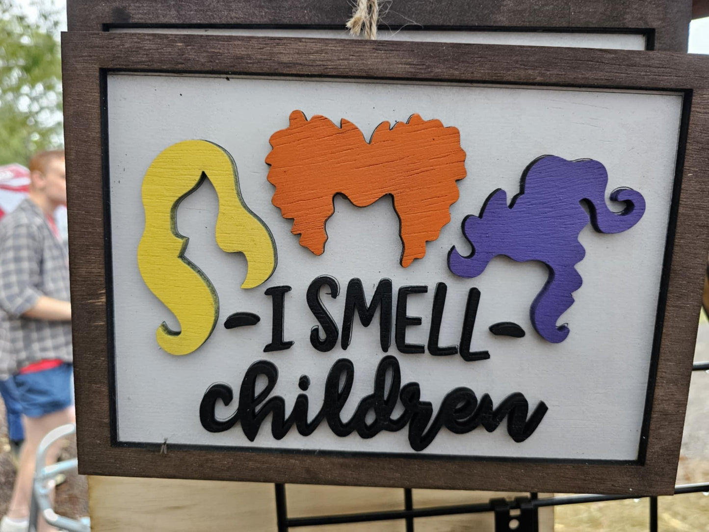 Custom wooden sign with colorful witch silhouettes and 'I Smell Children' text at Bearnugget Customs booth