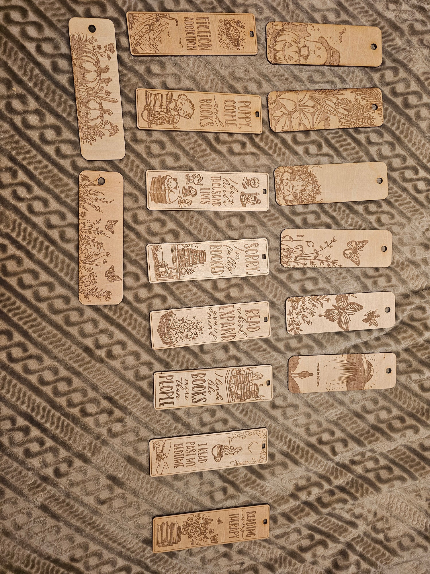 Assorted engraved wooden bookmarks with book and nature designs on patterned fabric, BearNugget Customs.