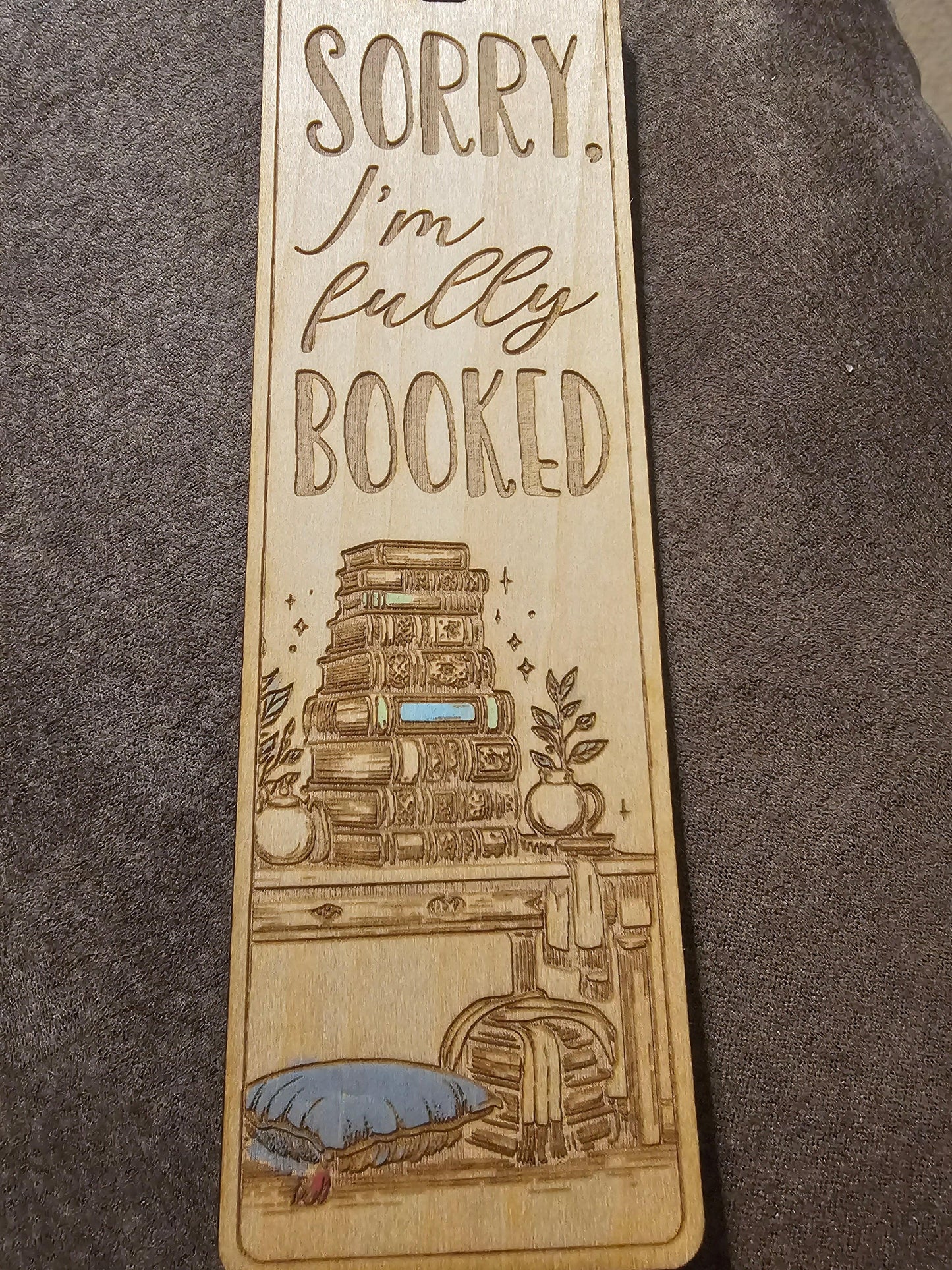 Custom wooden bookmark with engraved stacked books, plants, and 'Sorry, I'm fully booked' text.